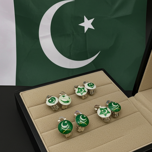 Six Pakistan-themed cufflinks displayed in an open beige jewelry box, with a green and white Pakistani flag in the background.