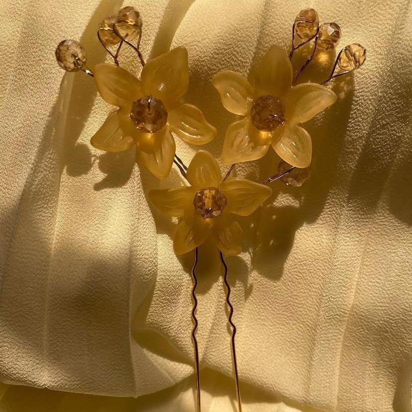 Yellow floral hairpin on a textured beige background