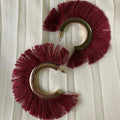 Pair of maroon fringe earrings on a white background