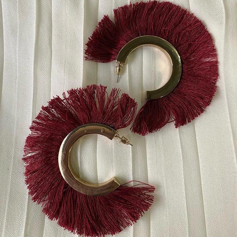 Pair of maroon fringe earrings on a white background