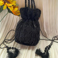Black beaded handbag with floral accents on a beige fabric background