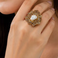 Gold ring with a pearl-like center on a hand