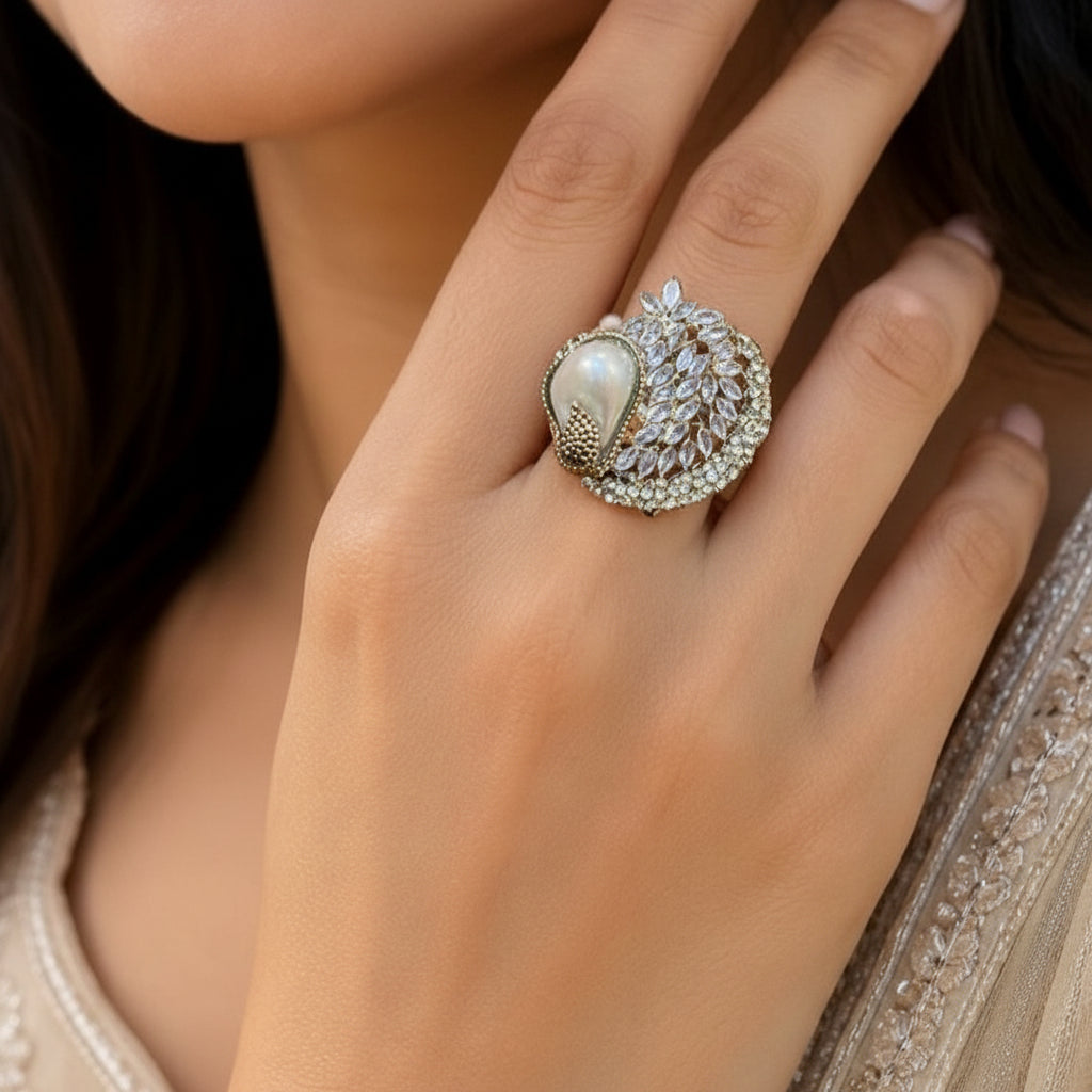 Close-up of a hand wearing an ornate ring with a pearl and gemstones.