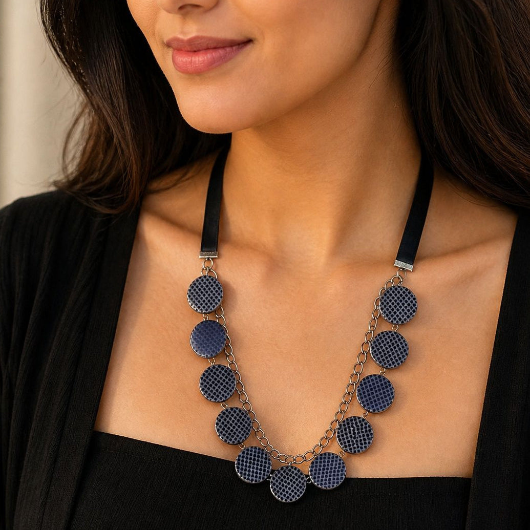 Woman wearing a blue patterned necklace with a blurred background