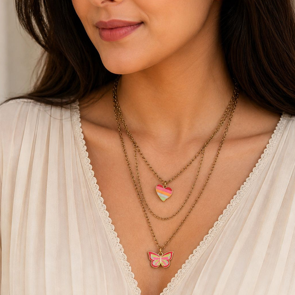 Woman wearing a necklace with a heart-shaped pendant and a butterfly pendant.