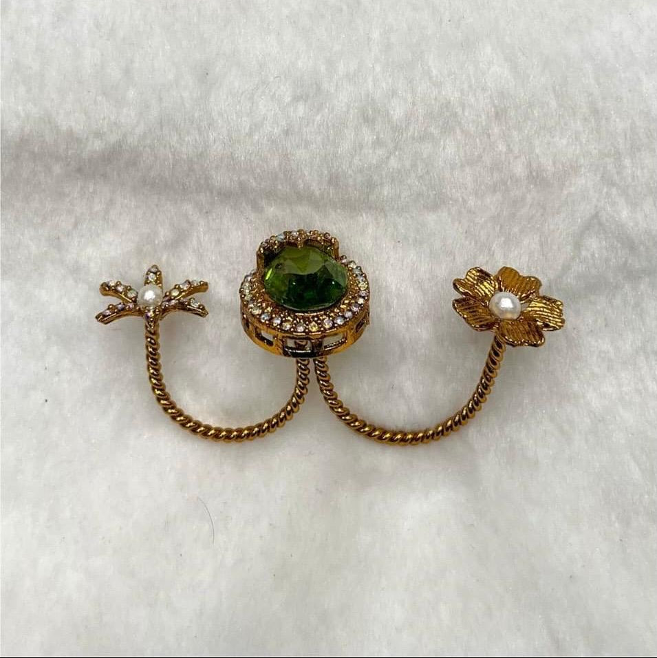 Gold earring with green gemstone and pearl on a white background