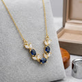 Gold necklace with blue gemstones on a gray surface