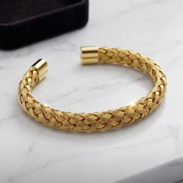Gold braided bracelet on a marble surface