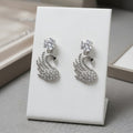 Silver swan-shaped earrings on a white card with a neutral background