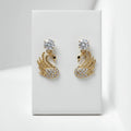 Gold swan-shaped earrings with crystal details on a white card