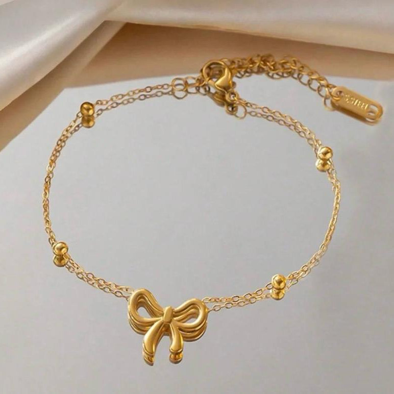 Gold bracelet with a bow charm on a light background