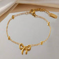 Gold bracelet with a bow charm on a light background