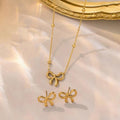 Gold bow-shaped necklace and earrings on a soft fabric background