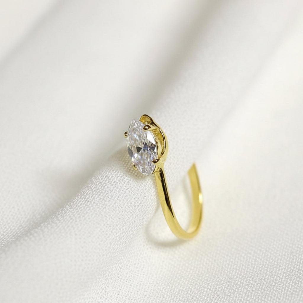 Gold earring with a diamond on a white fabric background