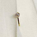 Gold earring with a clear gemstone on a white fabric background