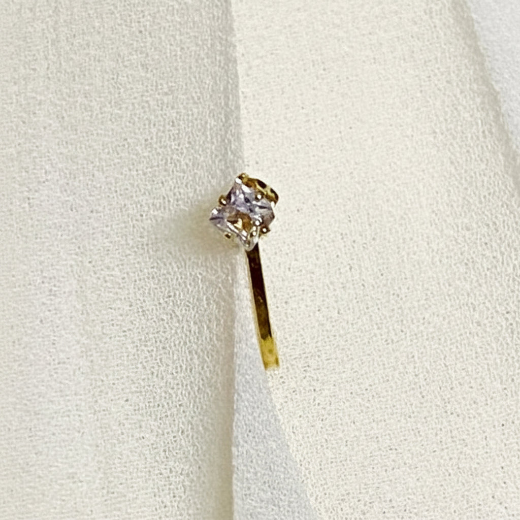 Gold earring with a clear gemstone on a white fabric background