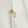 Gold earring with a small diamond on a white fabric background