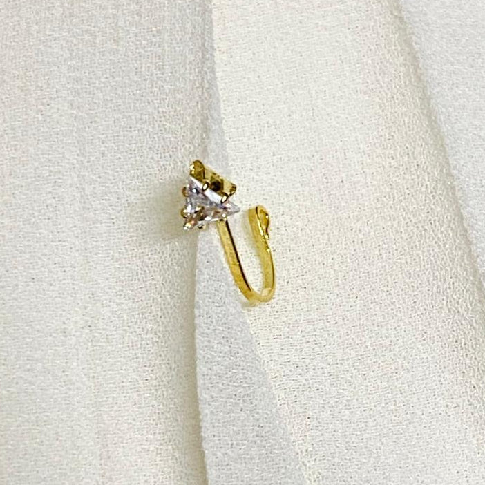 Gold earring with a small diamond on a white fabric background