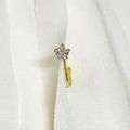 Gold earring with a star-shaped gemstone on a white textured background