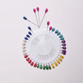 Colorful sewing pins arranged in a circular pattern on a white background