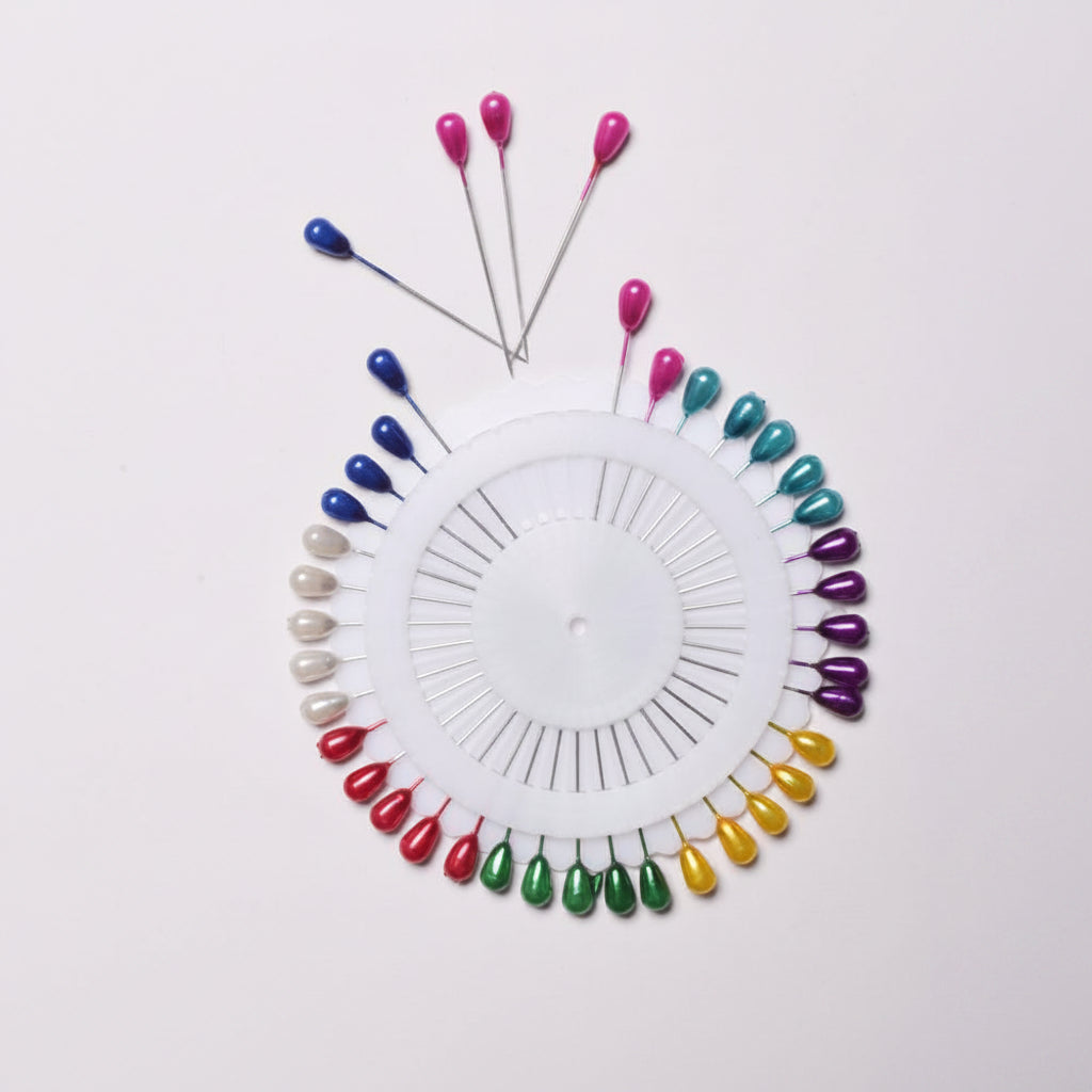 Colorful sewing pins arranged in a circular pattern on a white background