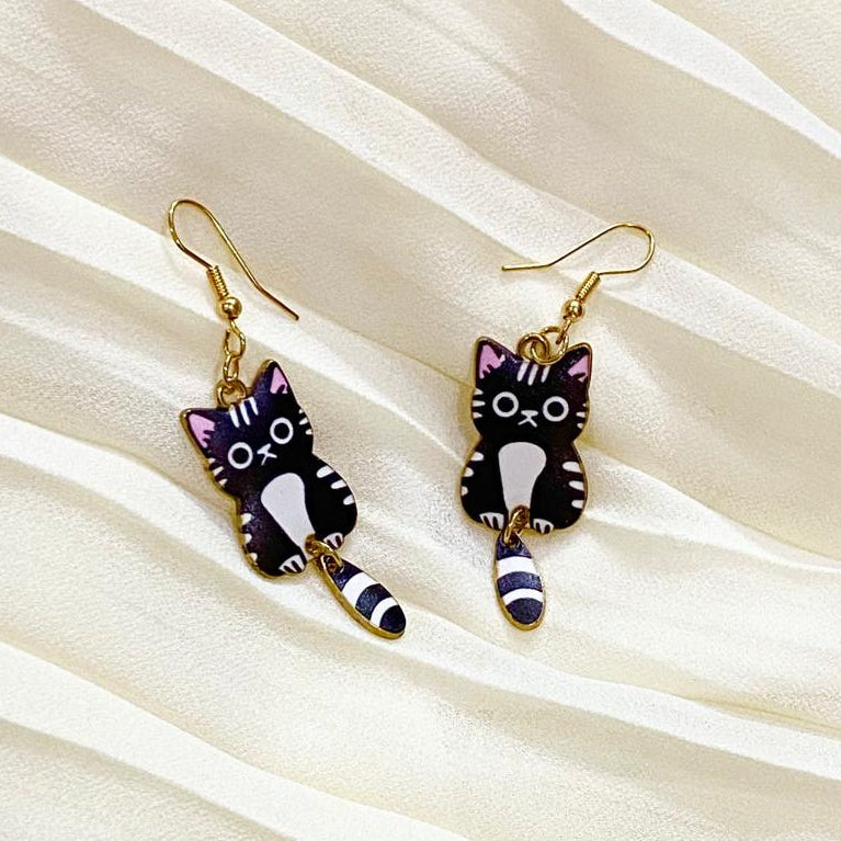 Cat-shaped earrings on a beige fabric background