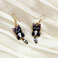 Cat-shaped earrings on a beige fabric background