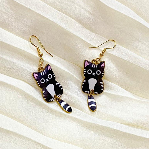 Cat-shaped earrings on a beige fabric background