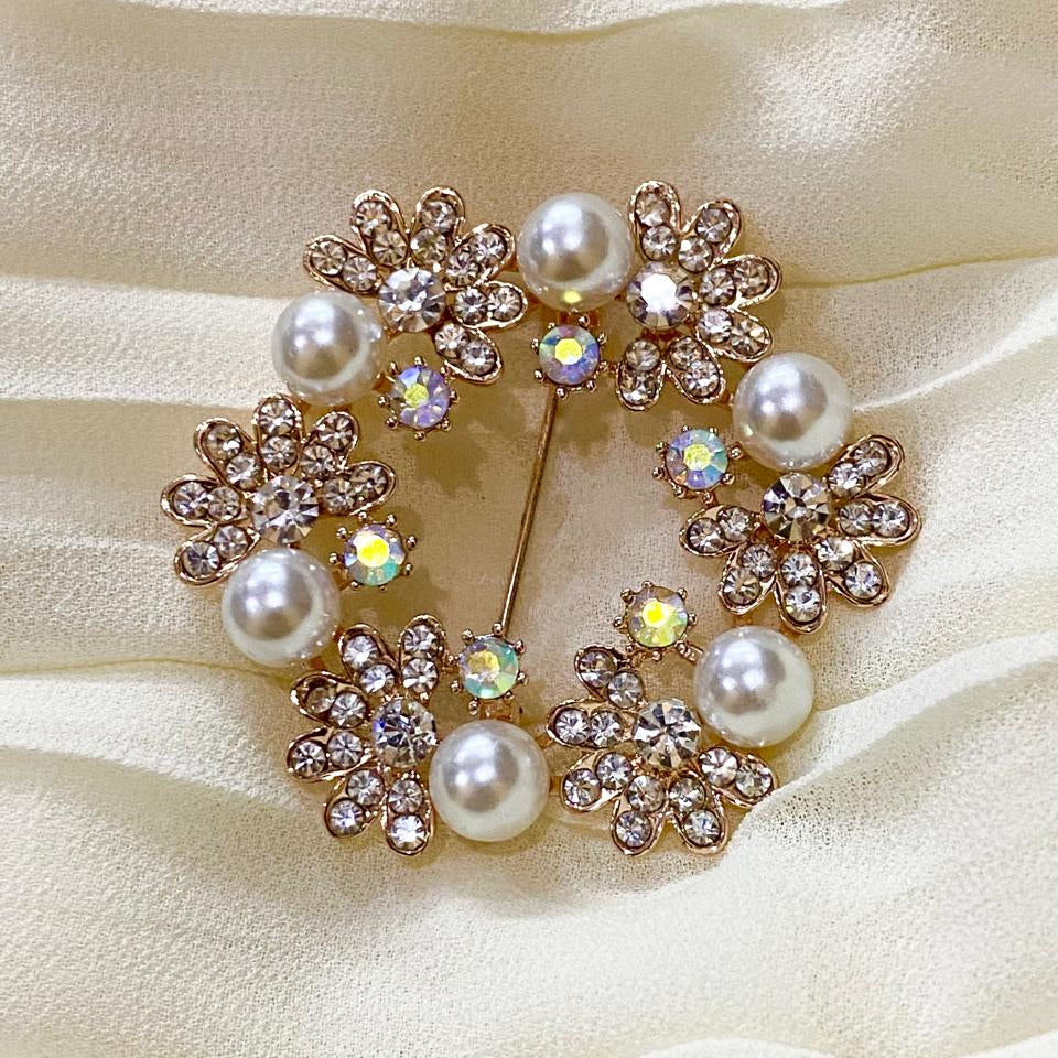 Decorative brooch with pearls and crystals on a beige fabric background
