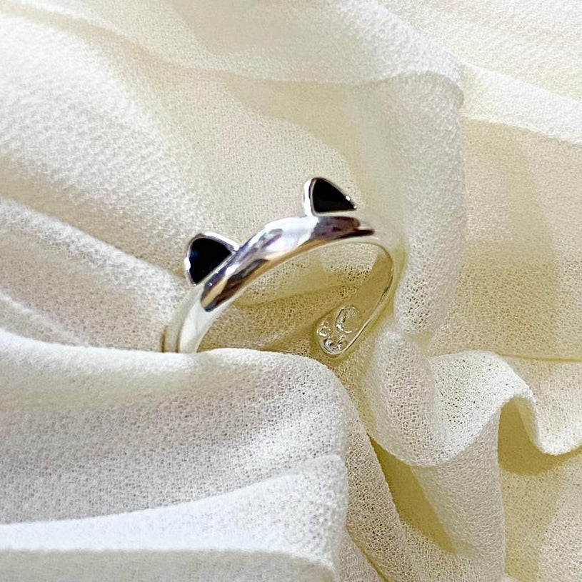 Silver cat-shaped ring on a soft white fabric background