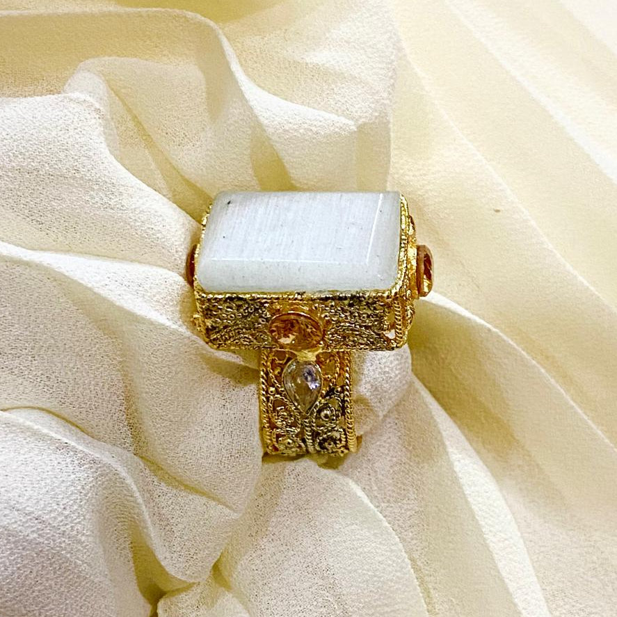 Gold ring with a light blue stone on a white fabric background