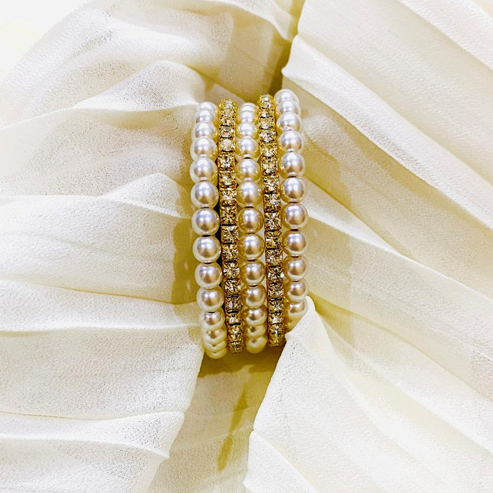 Set of pearl bracelets on a white fabric background