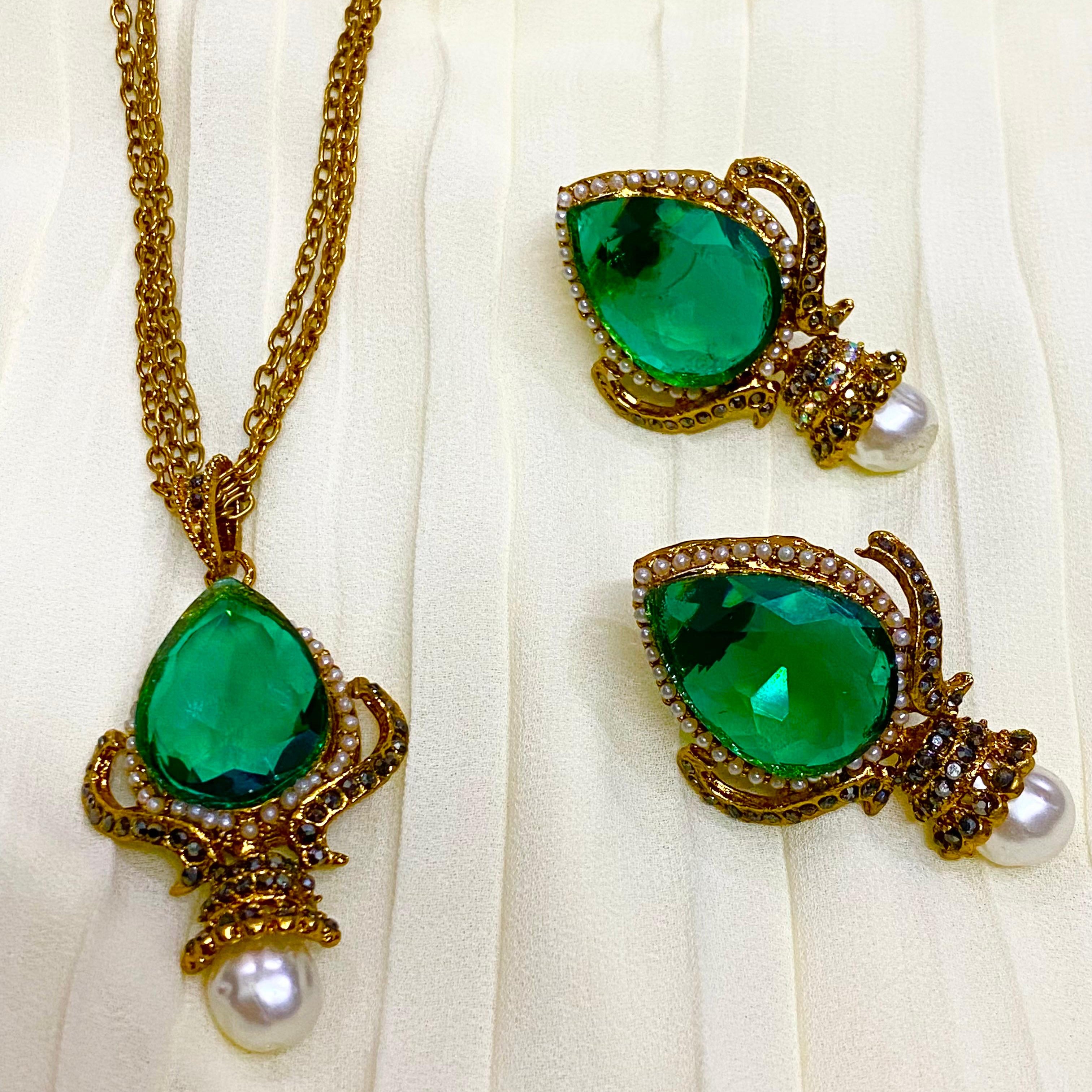 Jewelry set with green gemstones and gold accents on a white fabric background