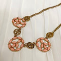 Necklace with pink floral pendants and gold chain on a white background