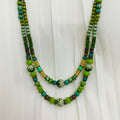 Green beaded necklace with decorative elements on a white fabric background