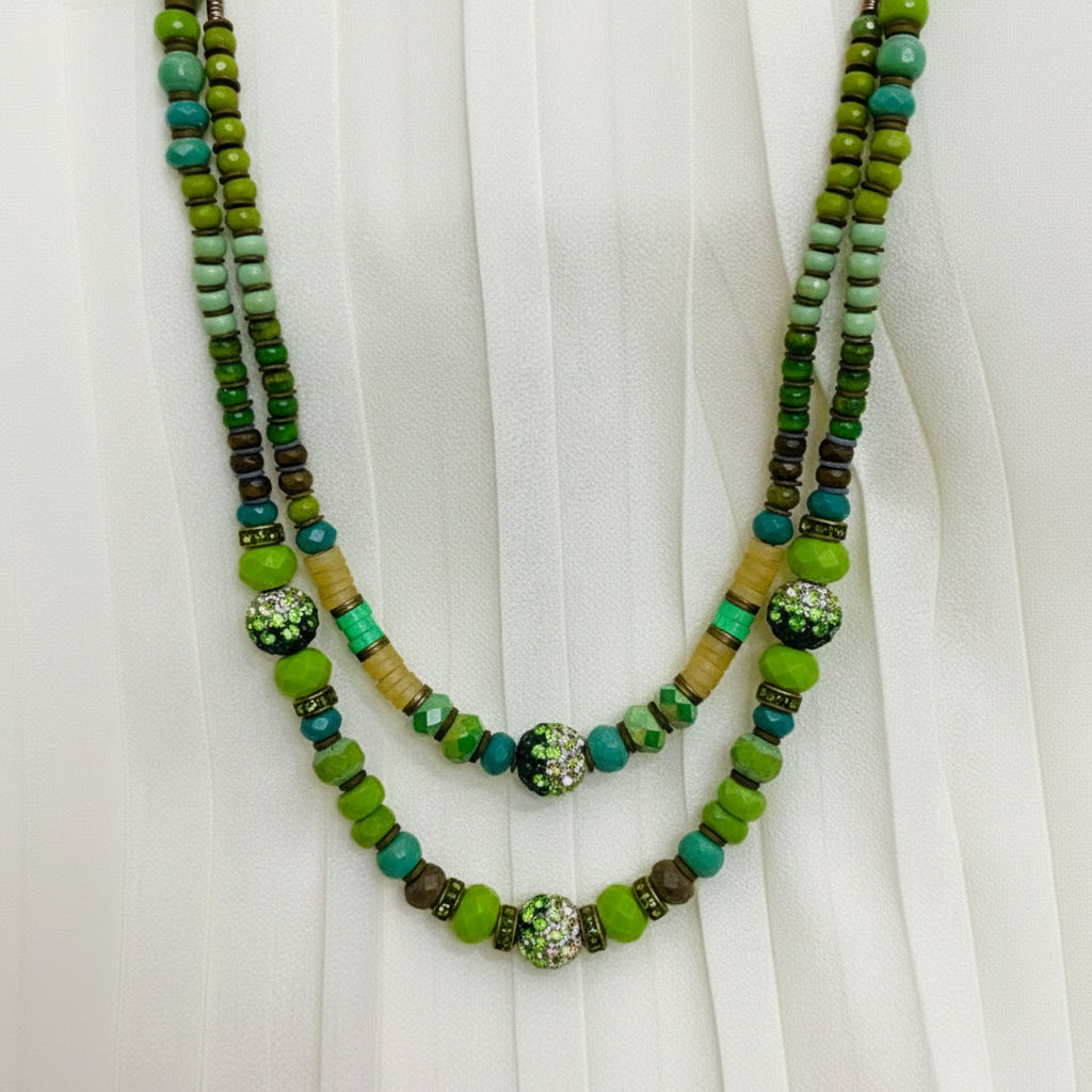 Green beaded necklace with decorative elements on a white fabric background