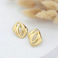 Gold earrings on a white surface with a fur texture background