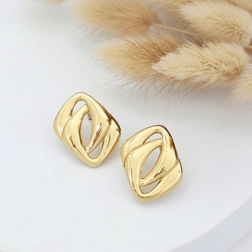 Gold earrings on a white surface with a fur texture background
