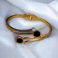 Gold bracelet with black stones on a white fabric background