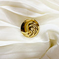 Gold decorative button on a white fabric background