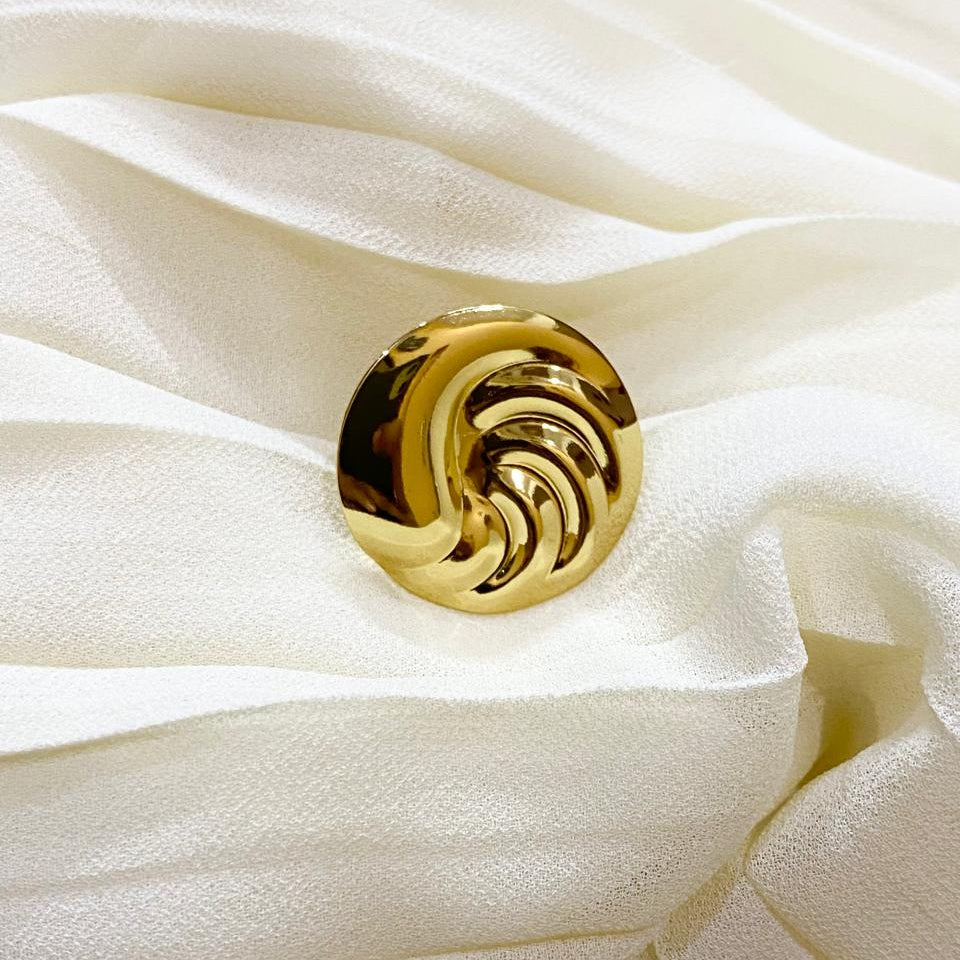 Gold decorative button on a white fabric background