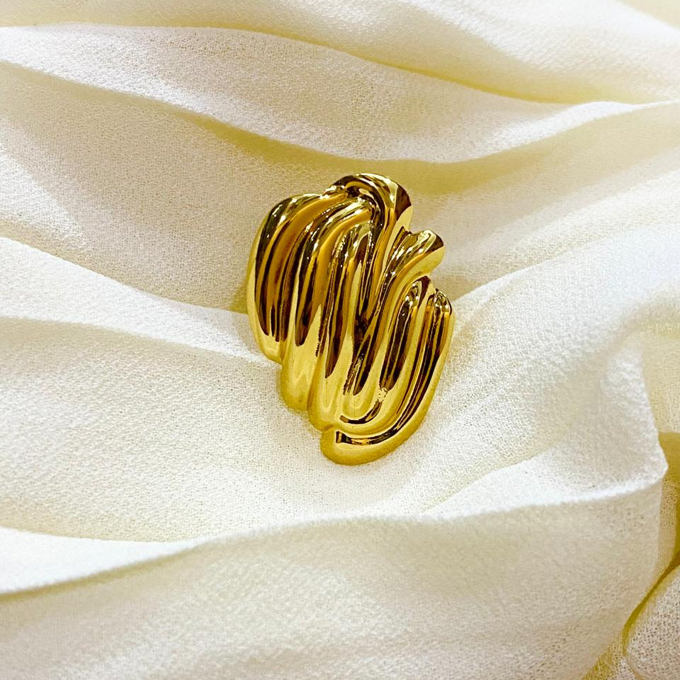 Gold ring with a textured design on a white fabric background