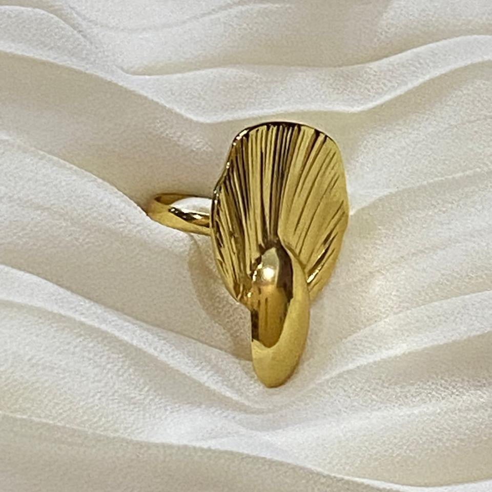 Gold ring with a unique design on a white fabric background