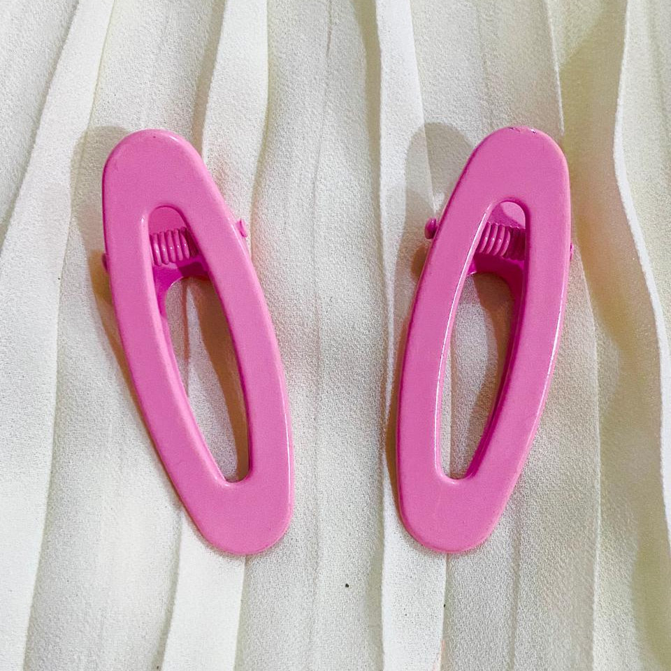 Two pink hair clips on a white fabric background