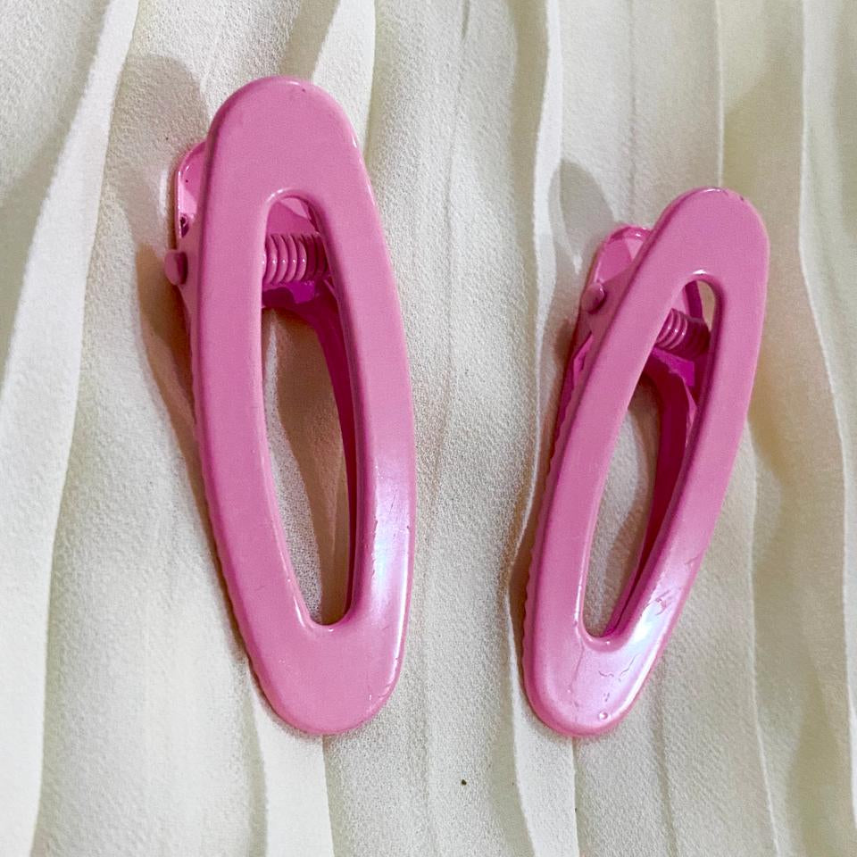 Two pink hair clips on a white fabric background