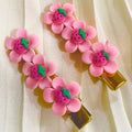Two pink flower-shaped hair clips on a beige fabric background