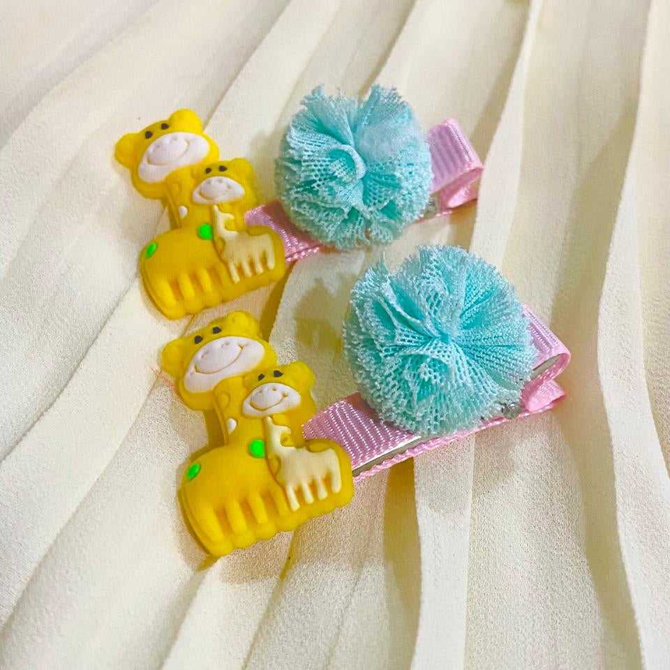 Two yellow monkey-shaped hair clips with blue sponge attachments on a white fabric background.