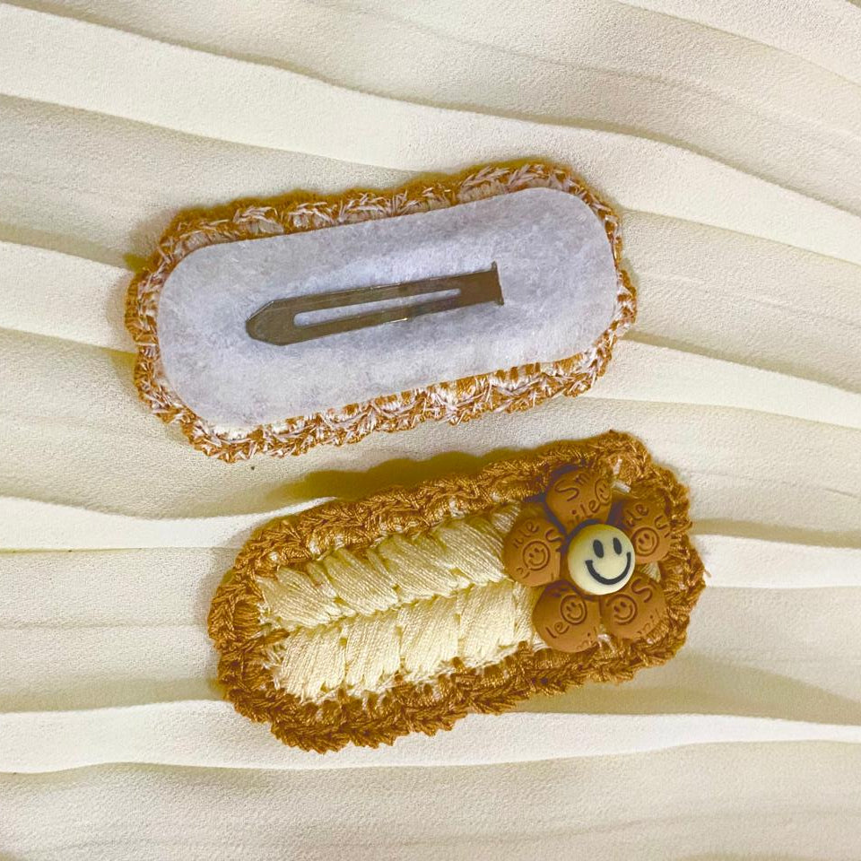 Two decorative hair clips on a sheer white fabric background