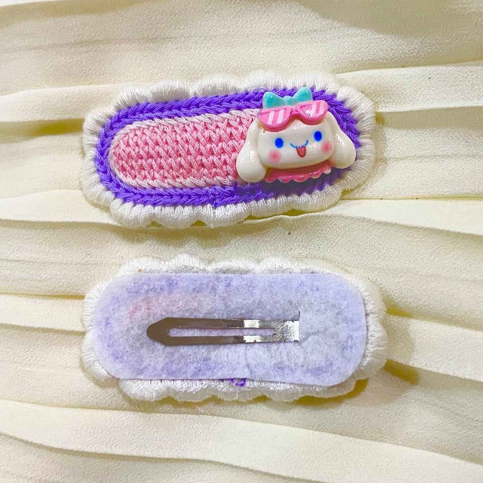 Two decorative hair clips on a light fabric background