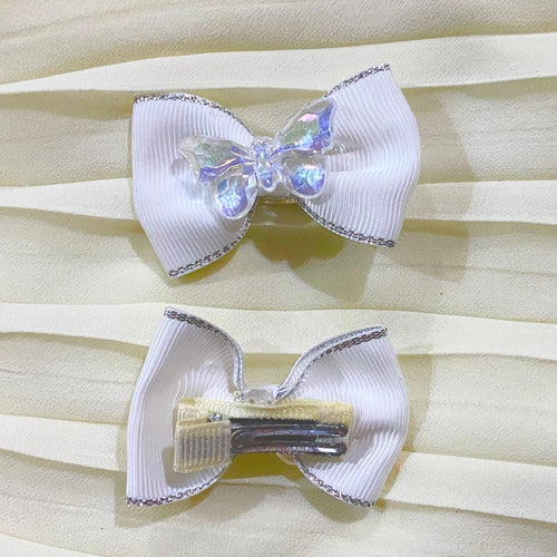 Two white hair bows with silver trim on a beige curtain background dreamy designs